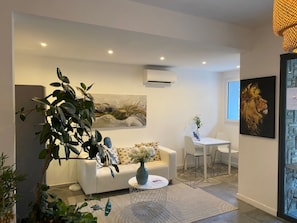 Una sala de estar moderna con un sofá blanco, una mesa de centro y una planta grande.