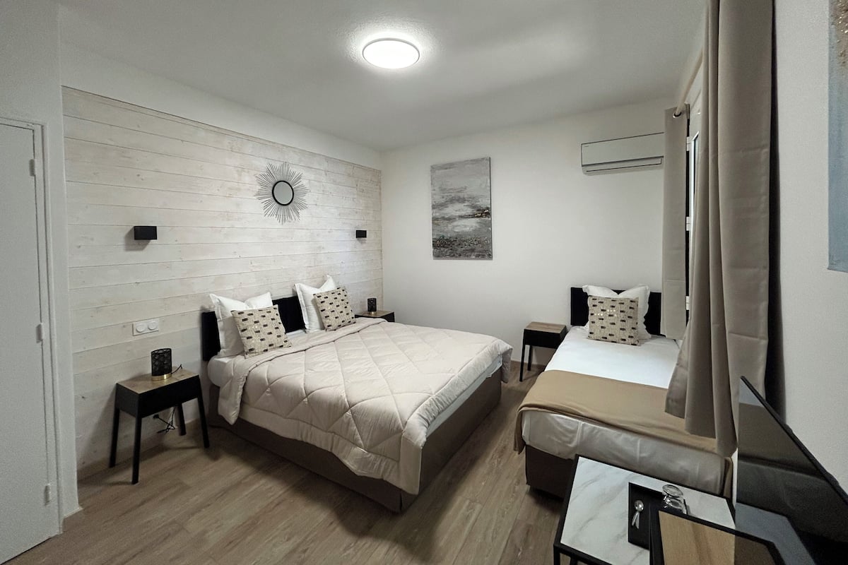 Un dormitorio con cama, mesitas de noche, un espejo y aire acondicionado instalado en la pared.