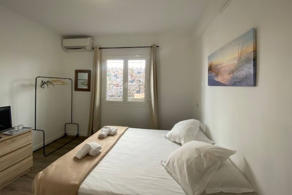 Une chambre d’hôtel avec un lit, un bureau, une chaise, une fenêtre avec des rideaux et un tableau au mur.