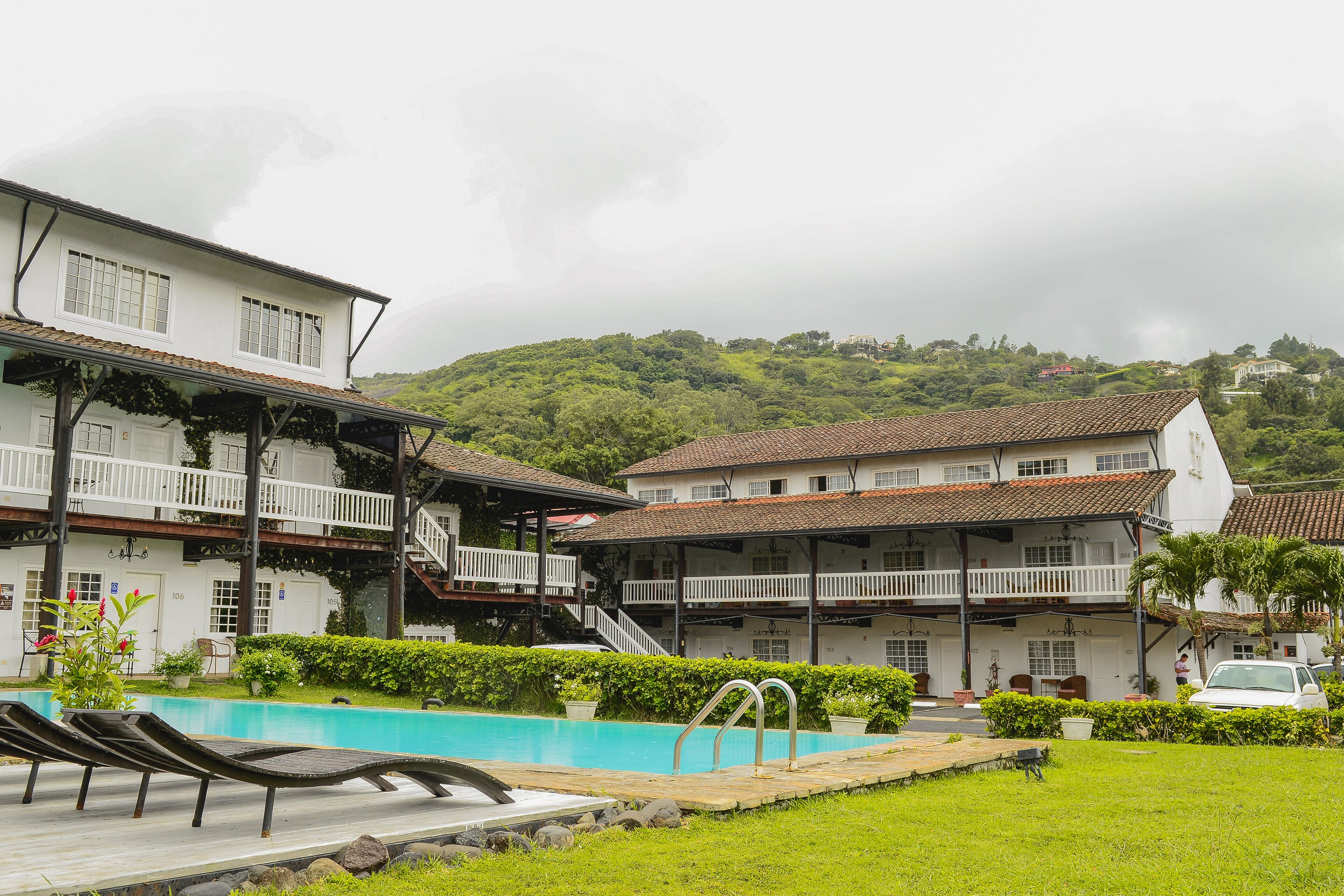 A hotel with a swimming pool, multiple balconies, and lush greenery.
