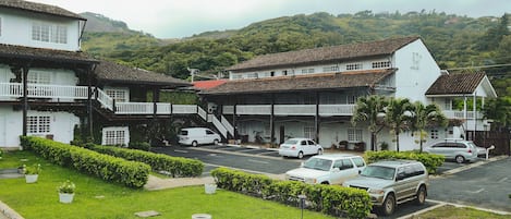 Um bairro residencial com casas brancas, uma rua e uma encosta ao fundo.