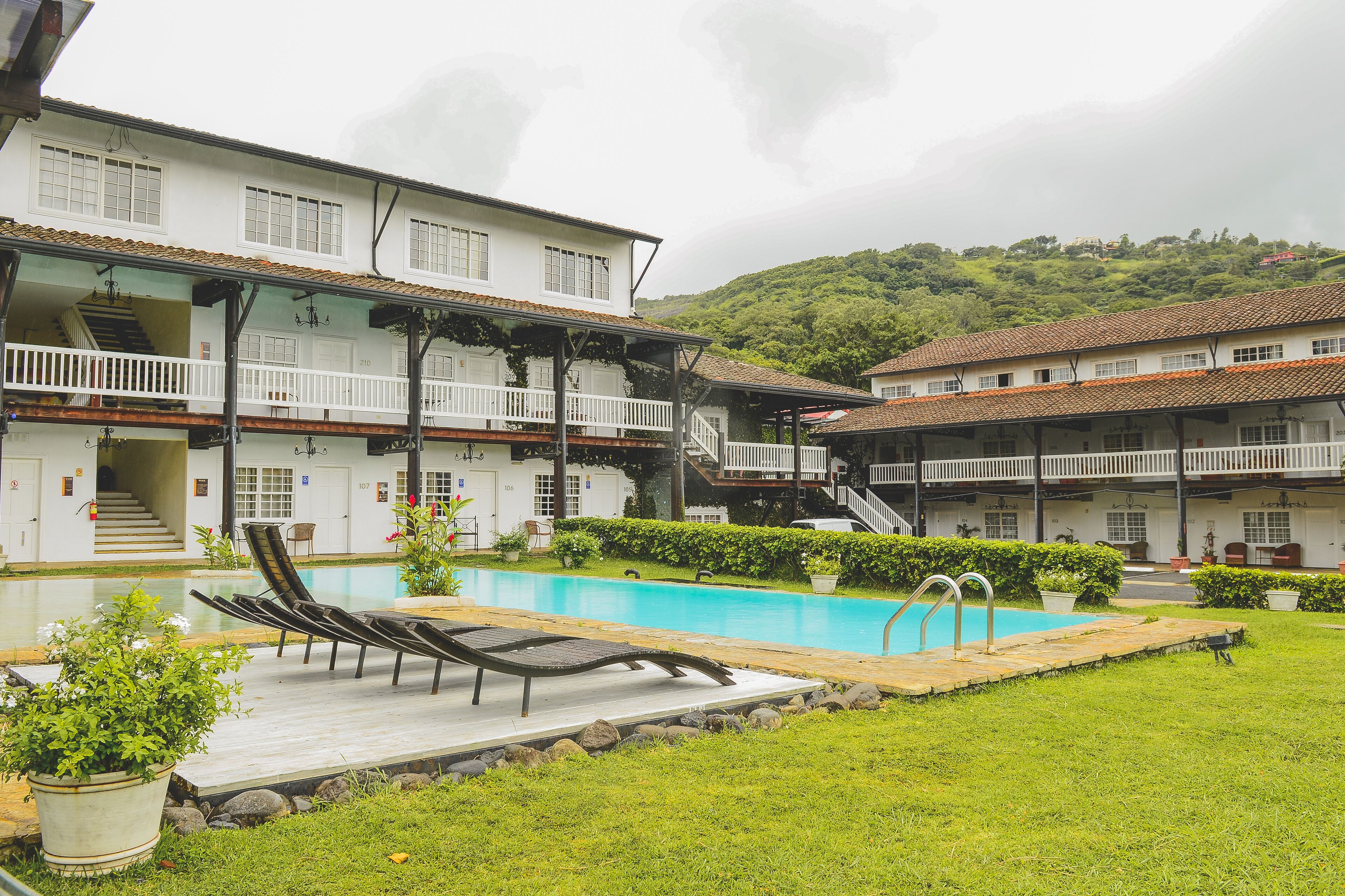 A hotel with a swimming pool, multiple balconies, and a staircase leading to the upper floors.