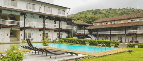 A hotel with a swimming pool, multiple balconies, and a staircase leading to the upper floors.