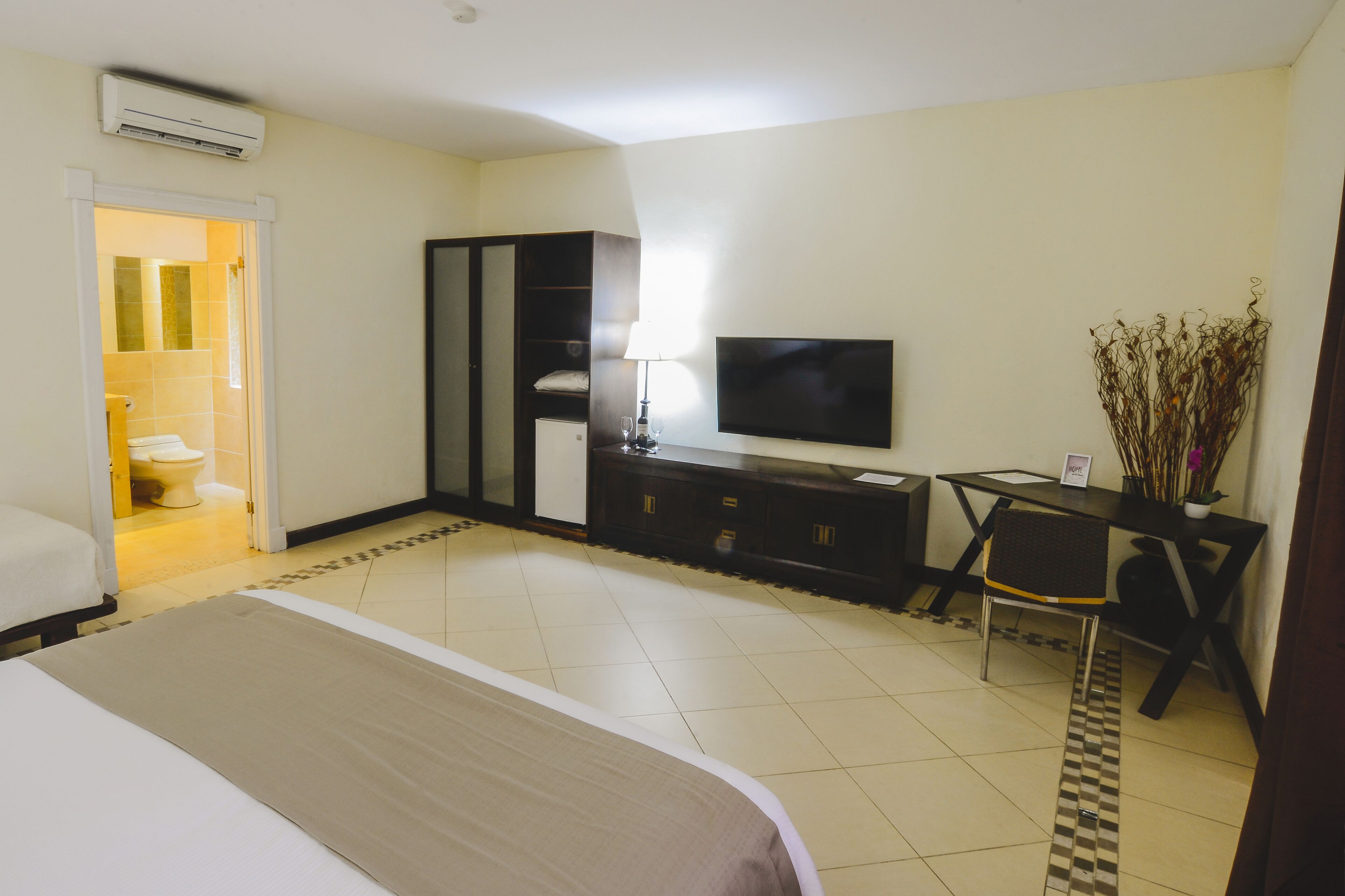 A hotel room with a bed, a desk with a chair, a TV, and a wardrobe.