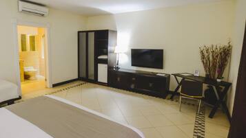 A hotel room with a bed, a desk with a chair, a TV, and a wardrobe.