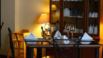 A dining table set for four with chairs, a lamp, and wine glasses.