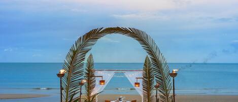 Decoración para una boda en la playa, con una carpa, sillas y una mesa.