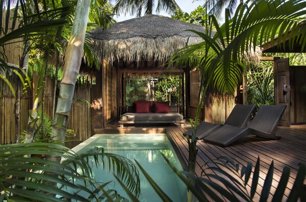 A pool area with a wooden deck, lounge chairs, and a thatched-roof structure with a bed. - Anantara Rasananda Koh Phangan Villas (Ko Pha-ngan)