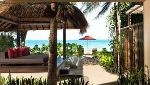 A covered outdoor seating area with a view of the ocean, a red umbrella, and tropical plants. - Anantara Rasananda Koh Phangan Villas (Ko Pha-ngan)
