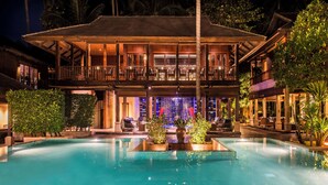 A resort with a large swimming pool, outdoor seating, and a well-lit building with multiple balconies. - Anantara Rasananda Koh Phangan Villas (Ko Pha-ngan)