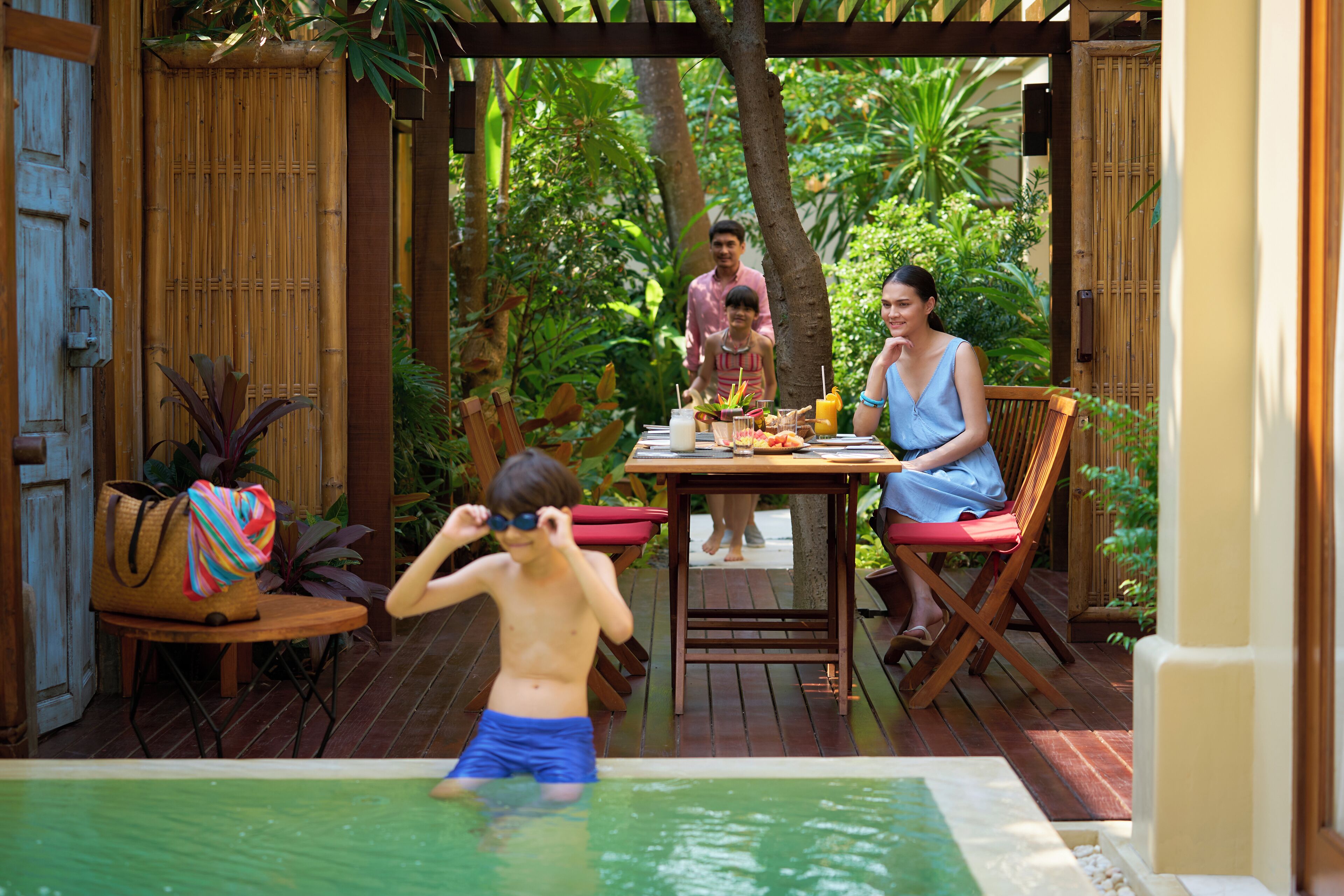 A wooden deck with a pool, surrounded by lush greenery.
