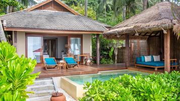 Un complexe hôtelier doté d’une piscine, d’une terrasse en bois et d’une structure à toit de chaume.