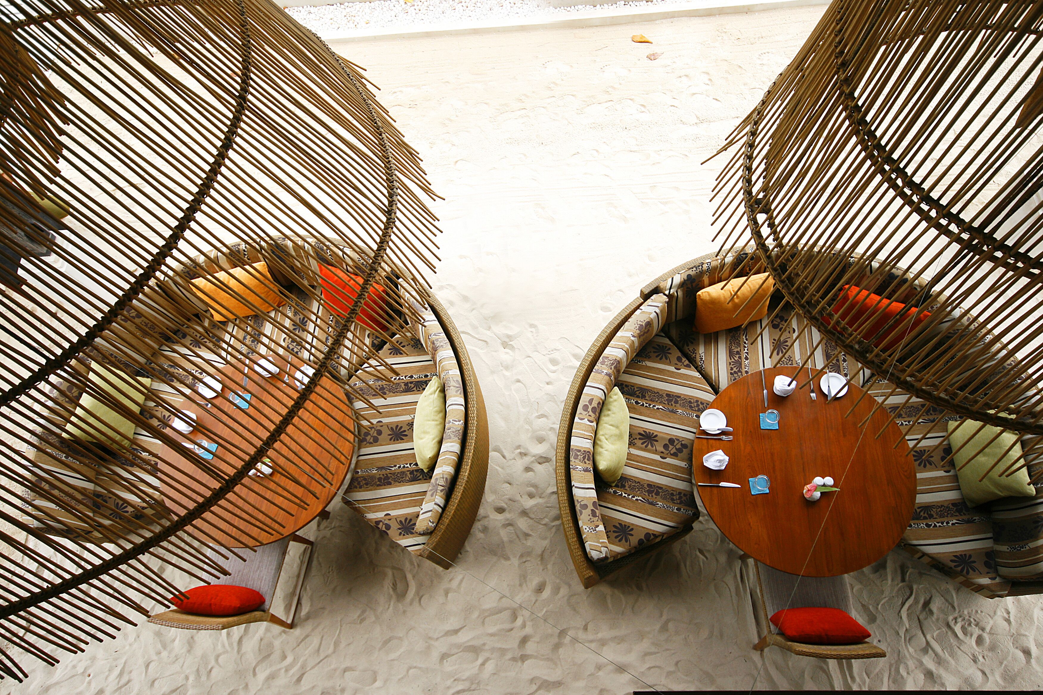 Two wicker chairs with cushions and a round wooden table, set on a textured floor.