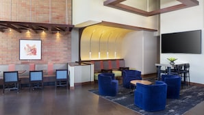 Un hall d’entrée moderne avec un mur en briques, un espace salon et un téléviseur à écran plat.