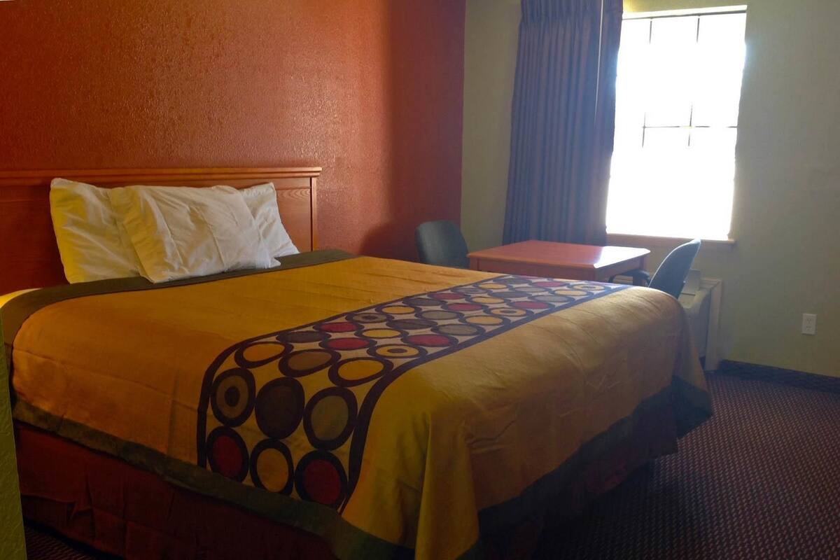 A hotel room with a bed, a desk, and a chair.