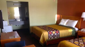 A hotel room with a bed, a desk, a chair, a nightstand, and a lamp. - Americas Best Value Inn Pryor (Pryor)