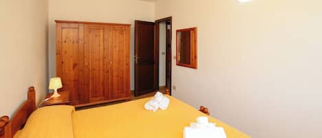 A bedroom with a bed, wooden wardrobe, and a mirror.