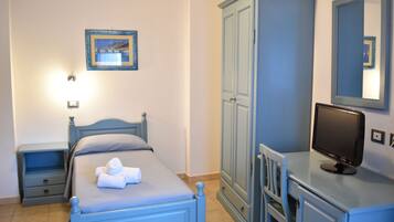 A bedroom with a bed, a nightstand, a wardrobe, a desk with a computer, and a mirror.
