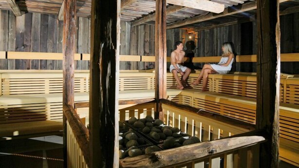Un sauna en bois avec des bancs, et un banc en bois au premier plan.