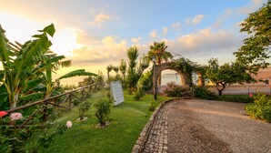 A garden pathway leading to a stone archway, surrounded by lush greenery and flowering plants. - Villa Irlanda Grand Hotel (Gaeta)
