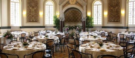 A banquet hall with round tables, chairs, and a central decorative archway.