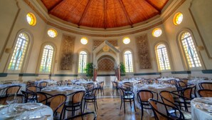 A spacious dining hall with high wooden ceilings, arched windows, and a central decorative archway. Tables are set with chairs, and the room is well-lit by natural light. - Villa Irlanda Grand Hotel (Gaeta)