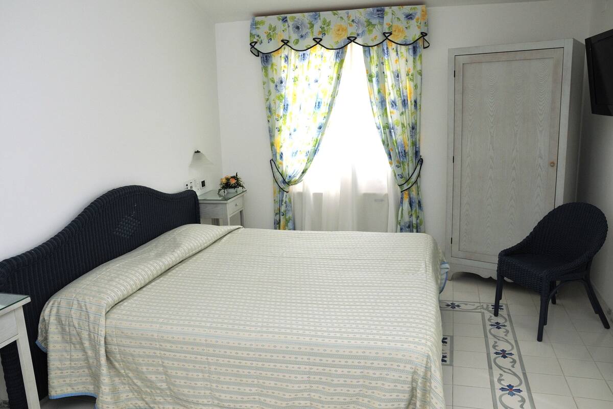 Une chambre à coucher avec un lit, une chaise, une table de chevet et une porte.