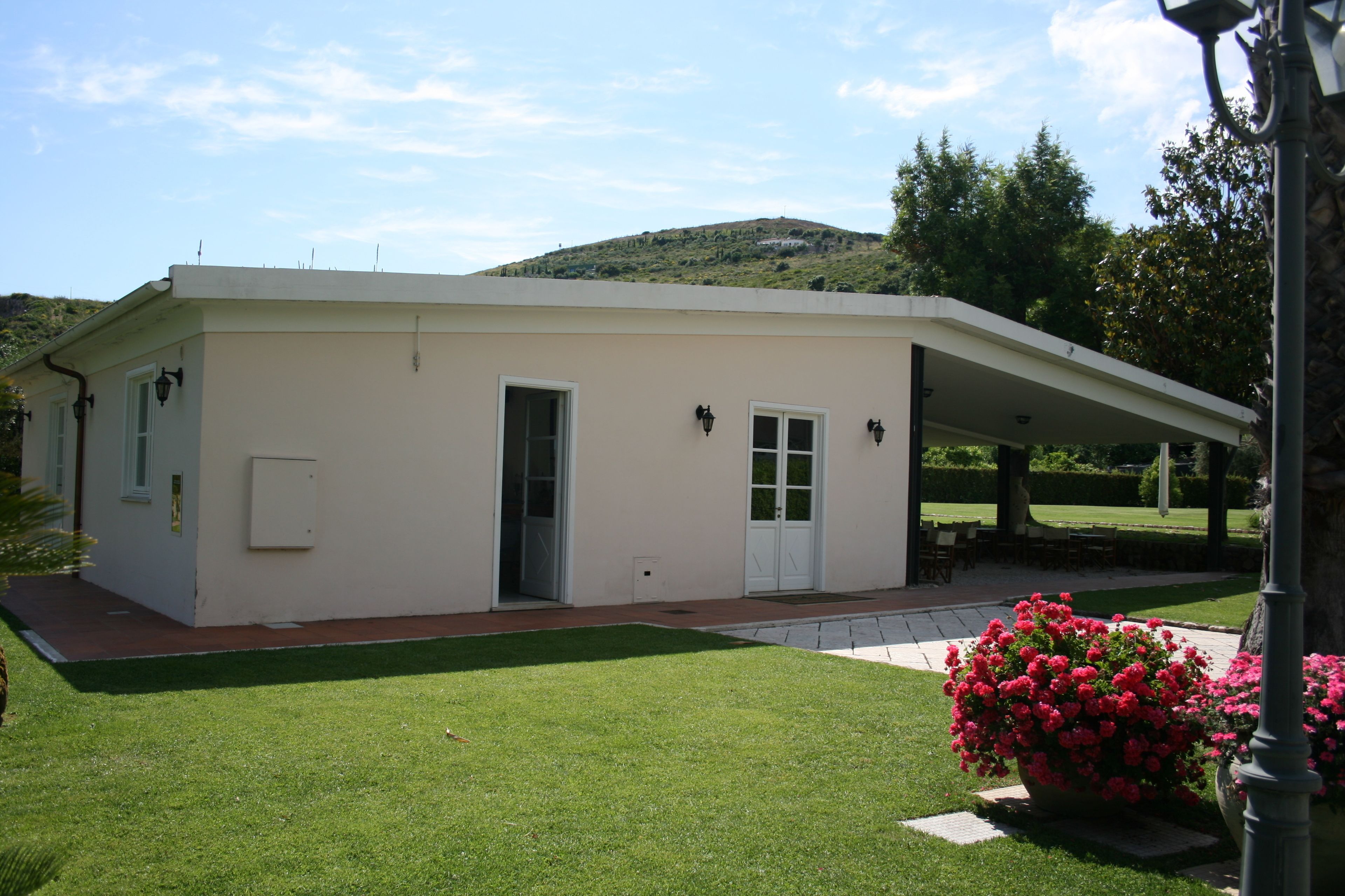A single-story building with a flat roof, a covered patio area, and a well-maintained lawn.