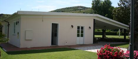 Un bâtiment d’un seul étage, doté d’un toit plat, d’un patio couvert et d’une pelouse bien entretenue.