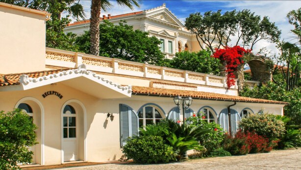 A building with a reception area, multiple windows with shutters, and a balcony with red flowers. - Villa Irlanda Grand Hotel (Gaeta)