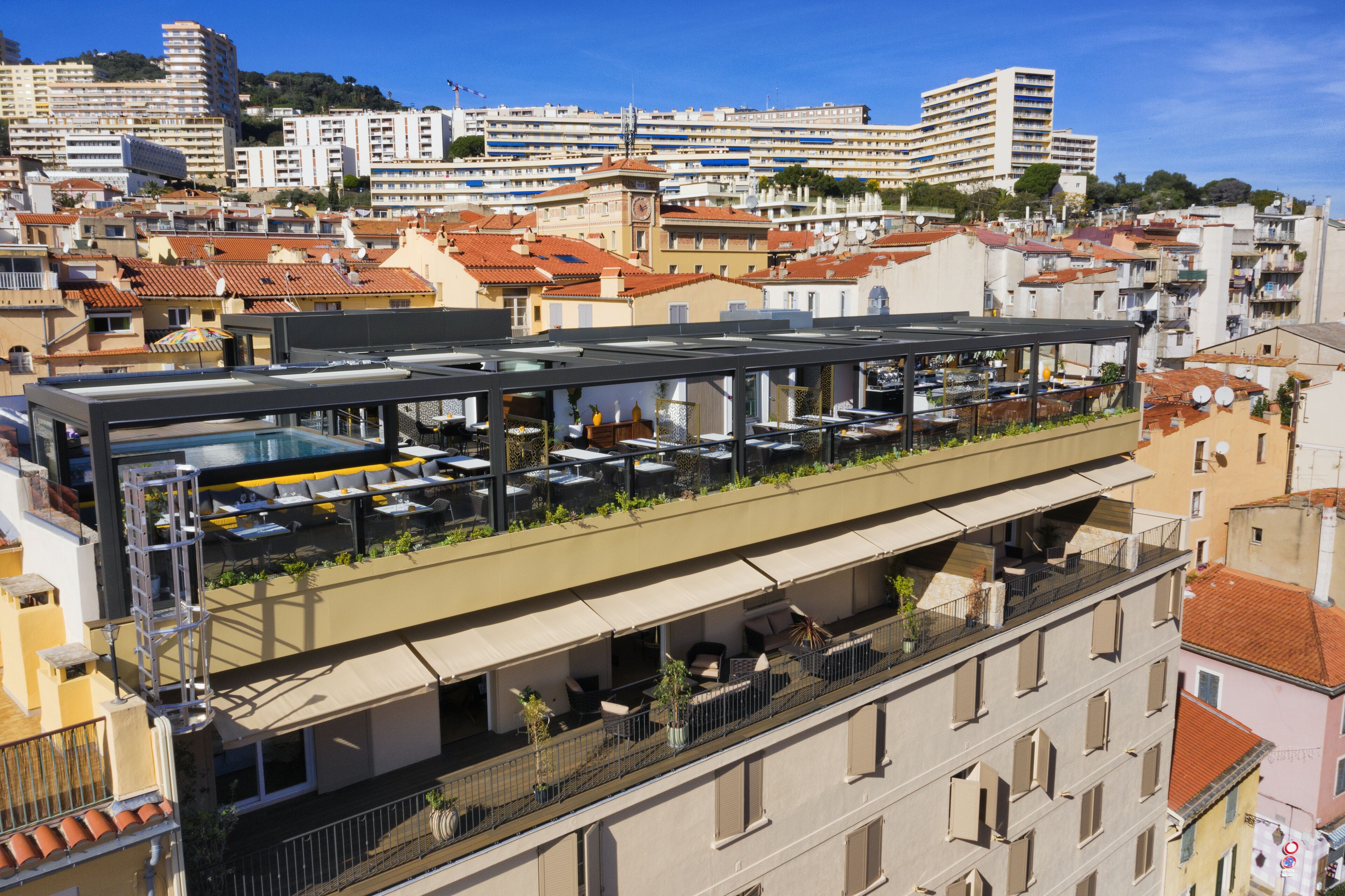 En restaurang på taket med uteservering, en pool och utsikt över stadsbilden.