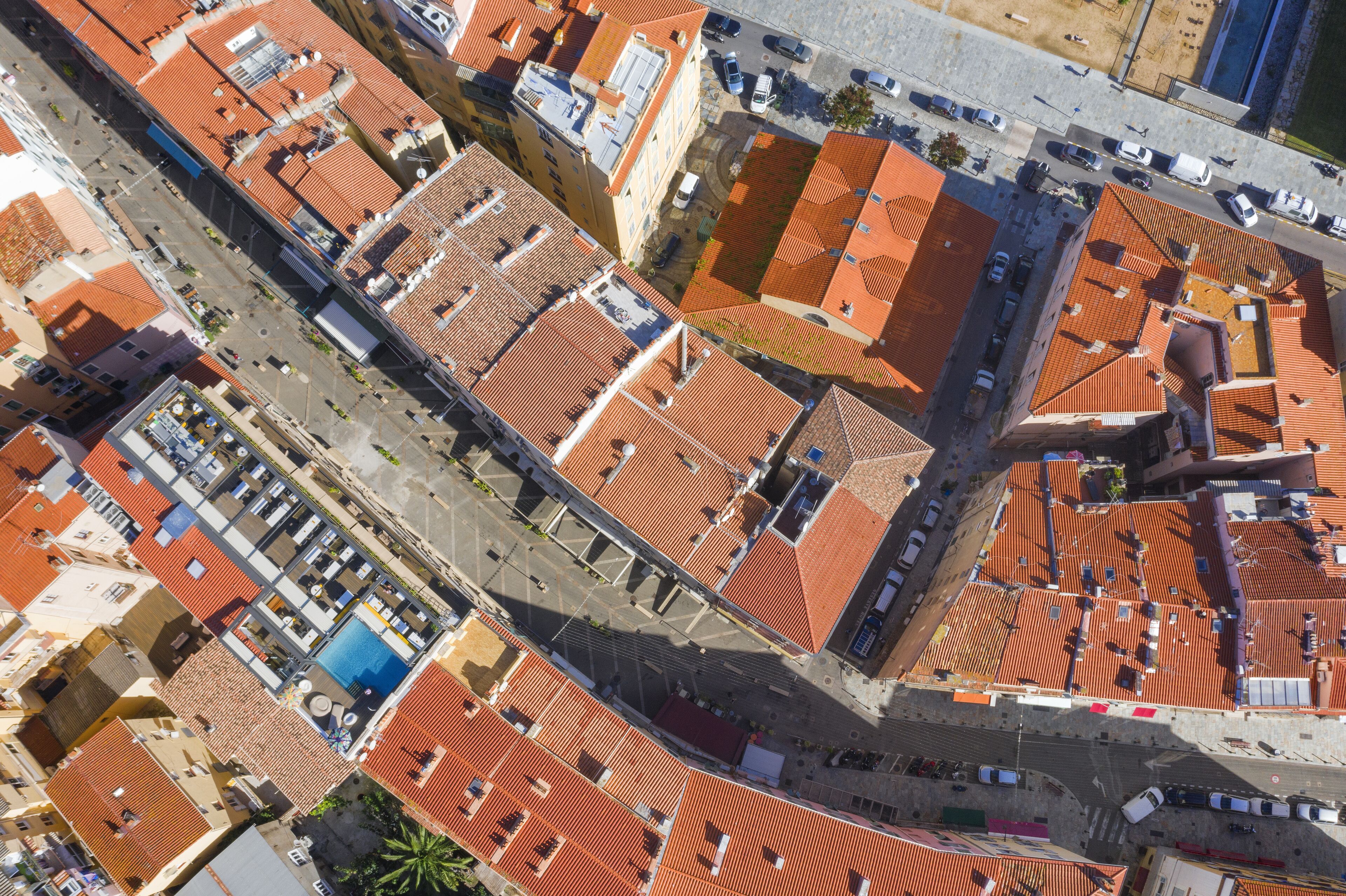 Luchtbeeld van een stadsgezicht met rode pannendaken, een centraal gelegen plein en een blauw gebouw met een zwembad.