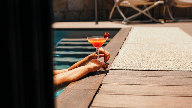A wooden deck with a pool, lounge chairs, and a drink. - Hôtel Fesch & Spa (Ajaccio)