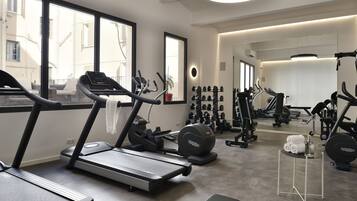 Un gimnasio moderno con cintas de correr, máquinas de pesas y una pequeña mesa con toallas.