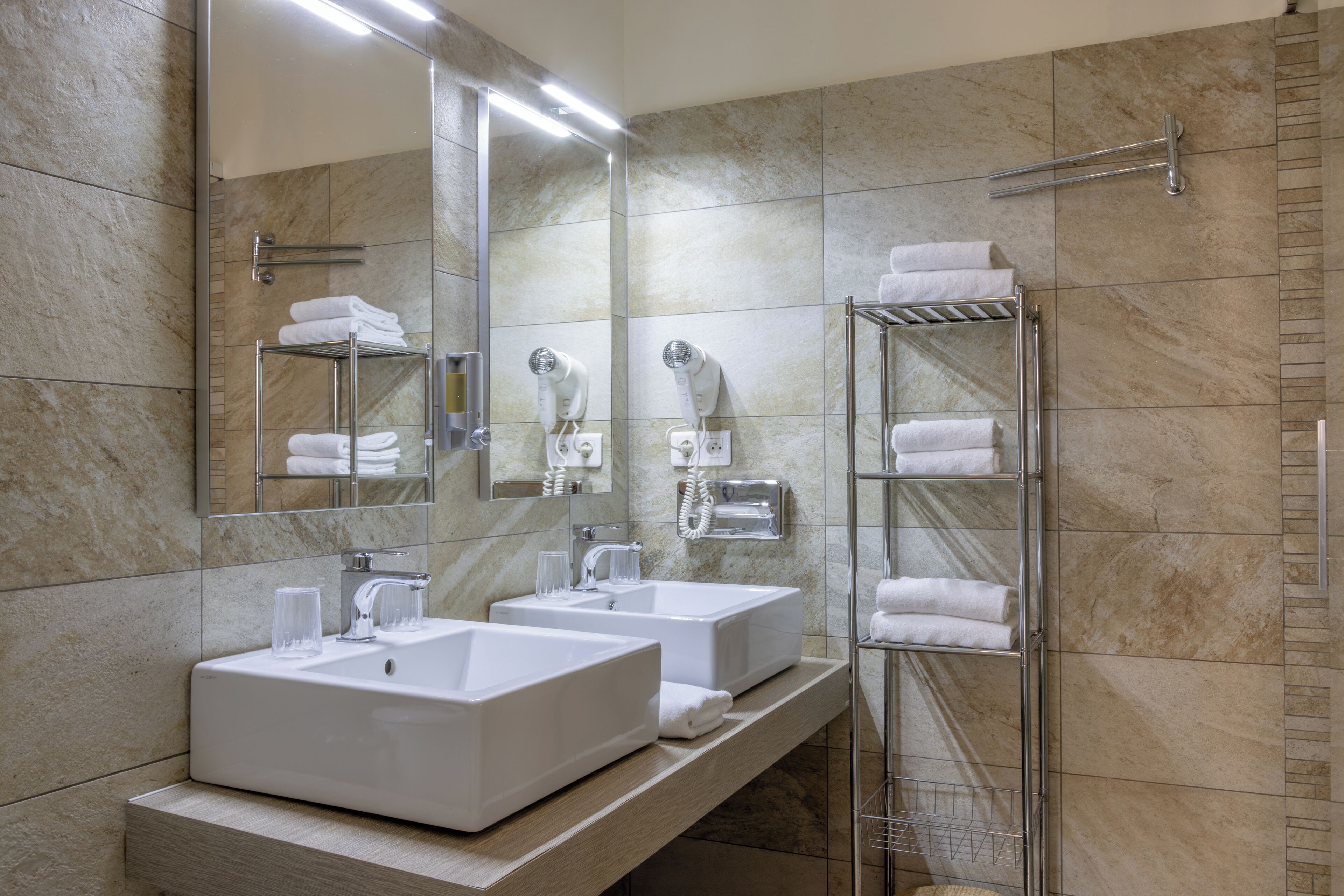 A modern bathroom with two sinks, a large mirror, and a glass shower enclosure.