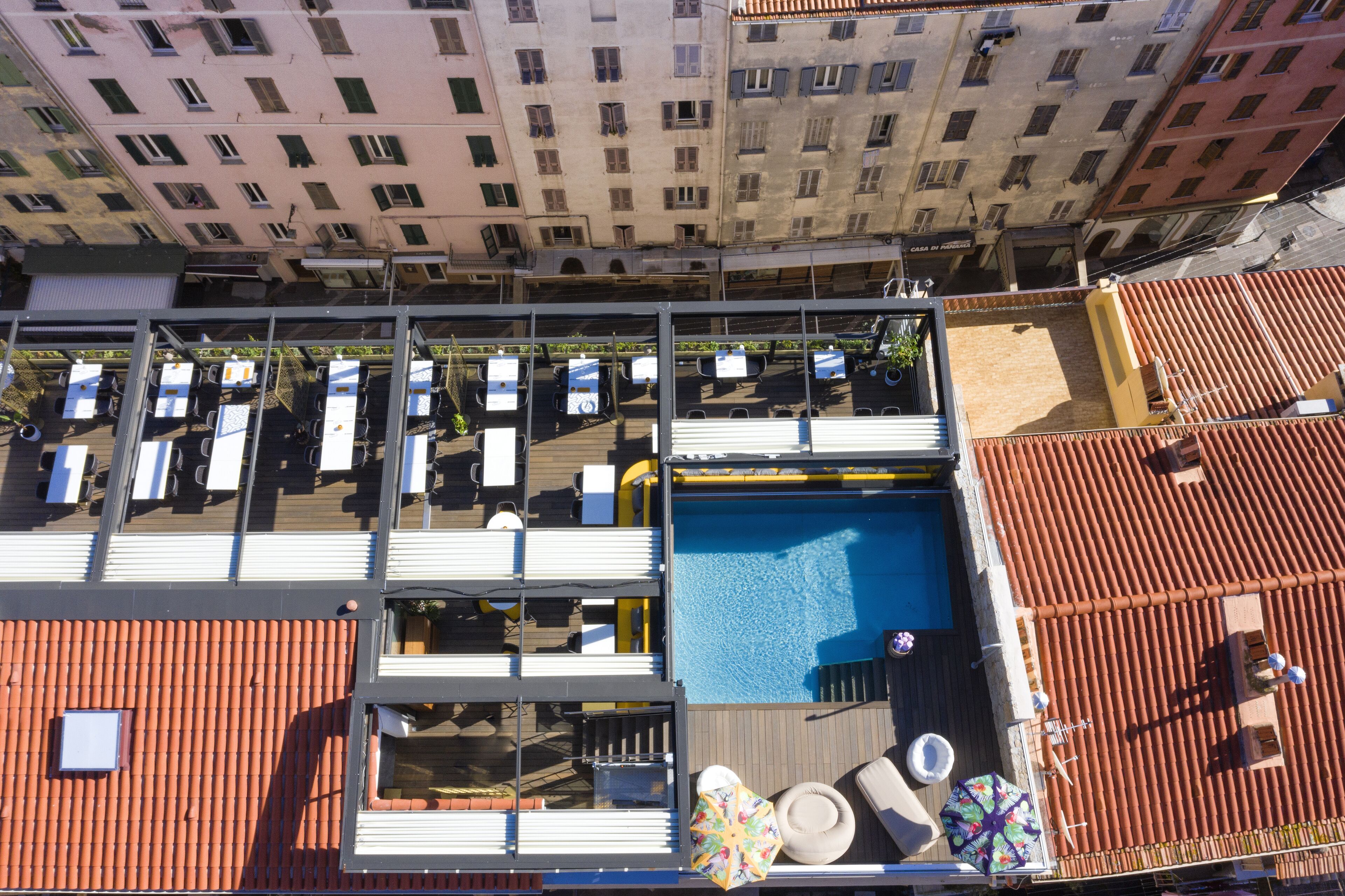 A rooftop pool area with lounge chairs, a pool, and a view of surrounding buildings.