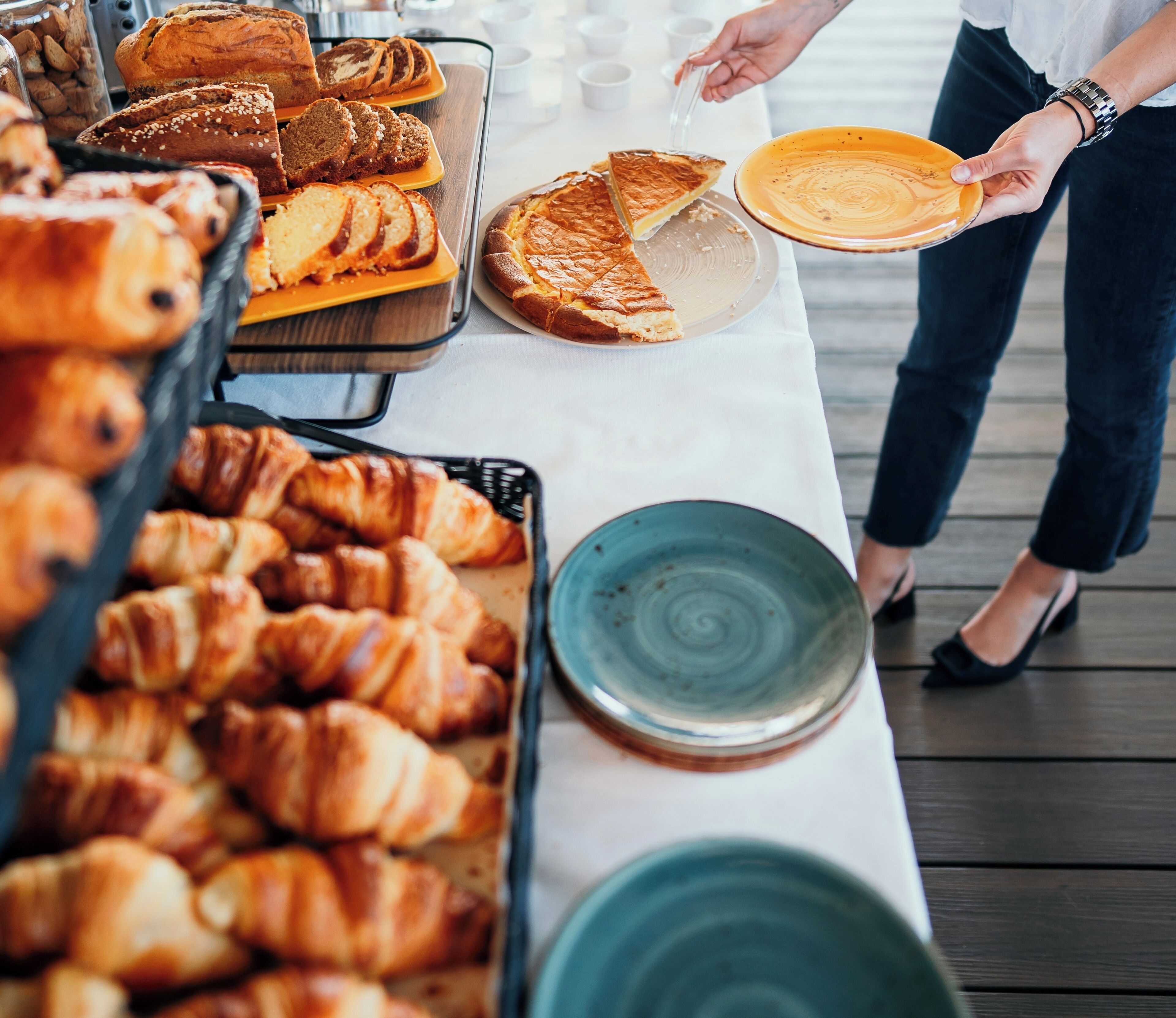 Uma mesa de buffet com diversos produtos de panificação, incluindo doces e tortas.