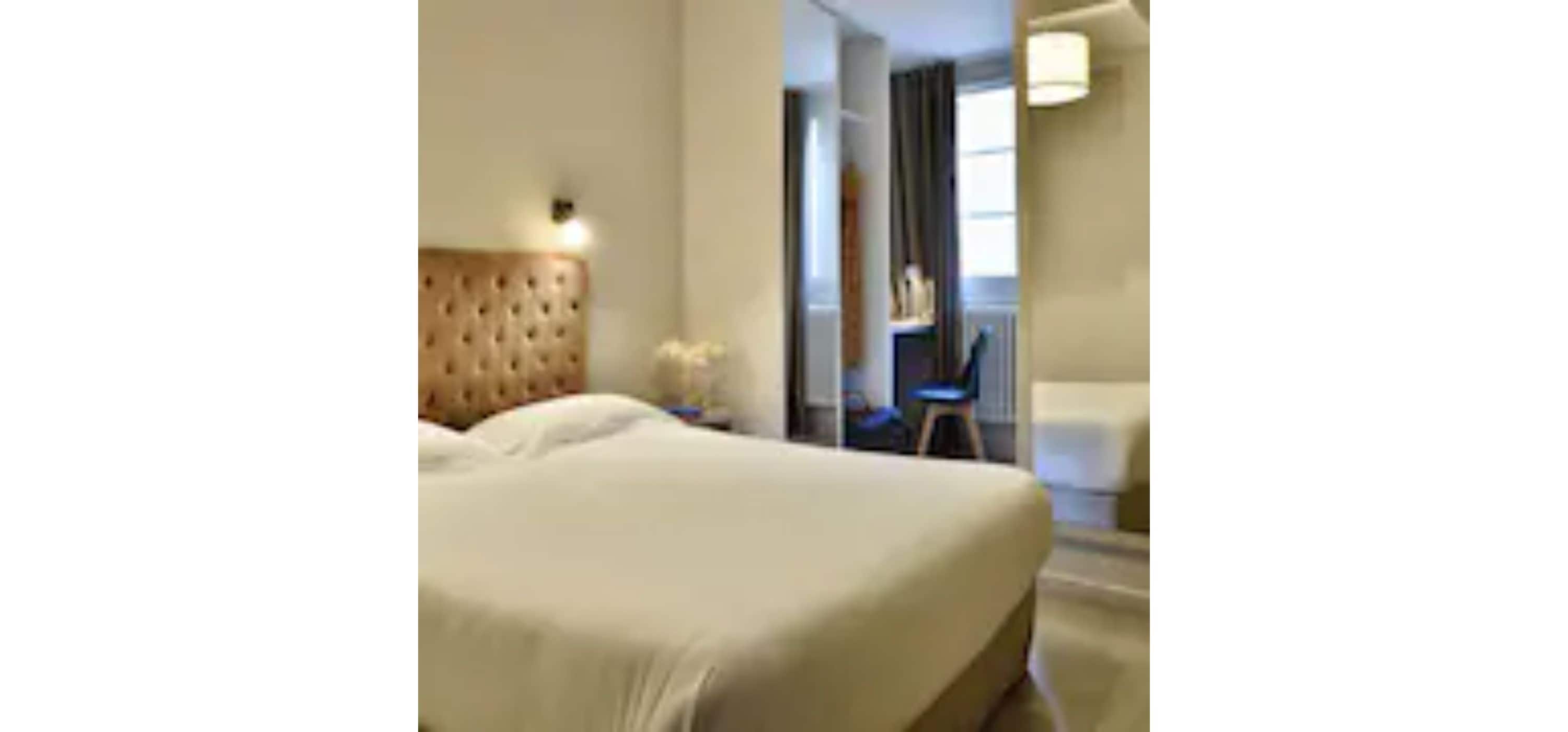 A hotel room with a large bed, a nightstand, a chair, and a desk.