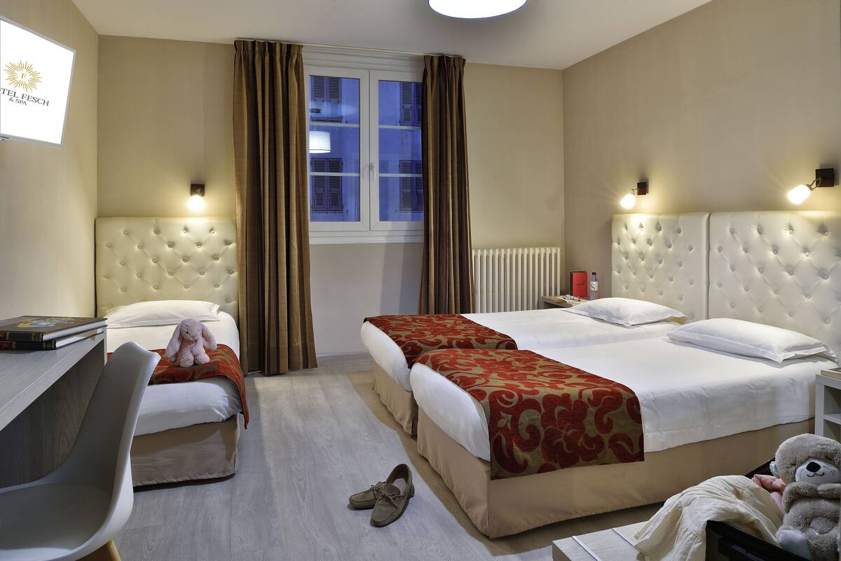 A hotel room with two beds, a desk, and a chair.