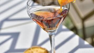 A clear glass cocktail with a citrus garnish on a white table with geometric patterns.
