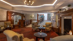 A spacious lobby with a grand staircase, comfortable seating, and a fireplace. - The Court Yard Hotel (Leixlip)