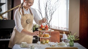 A person serving a tiered dessert tray with various pastries and fruits. - The Court Yard Hotel (Leixlip)