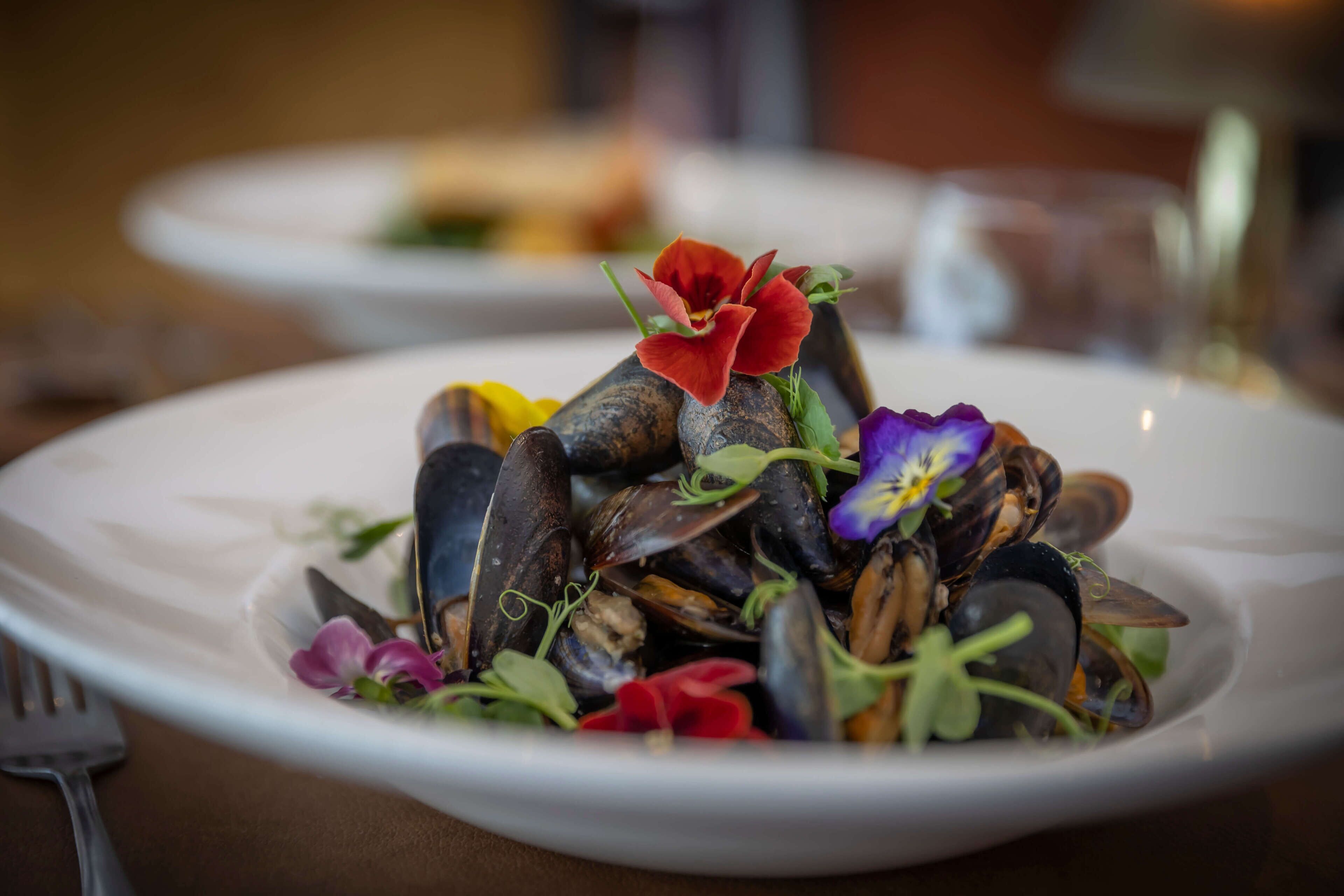 A plate of mussels with flowers on a white plate.