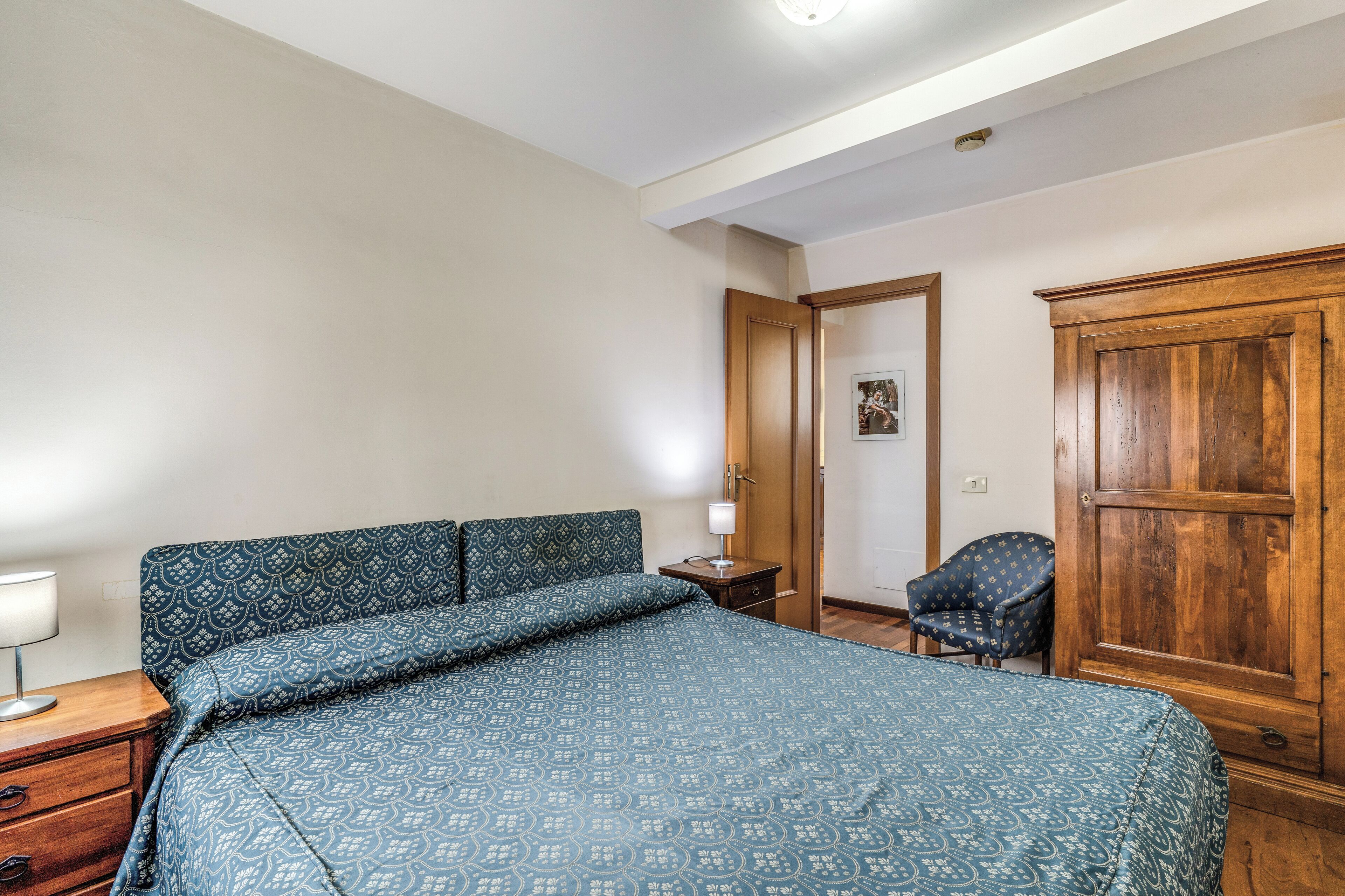 Ein Schlafzimmer mit Bett, Stuhl, Kleiderschrank und Nachttisch.