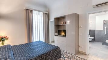 A hotel room with a bed, a TV, a minibar, and a bathroom visible through an open door.