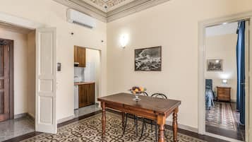 A dining area with a wooden table and chairs, a patterned floor, and a ceiling with decorative molding.