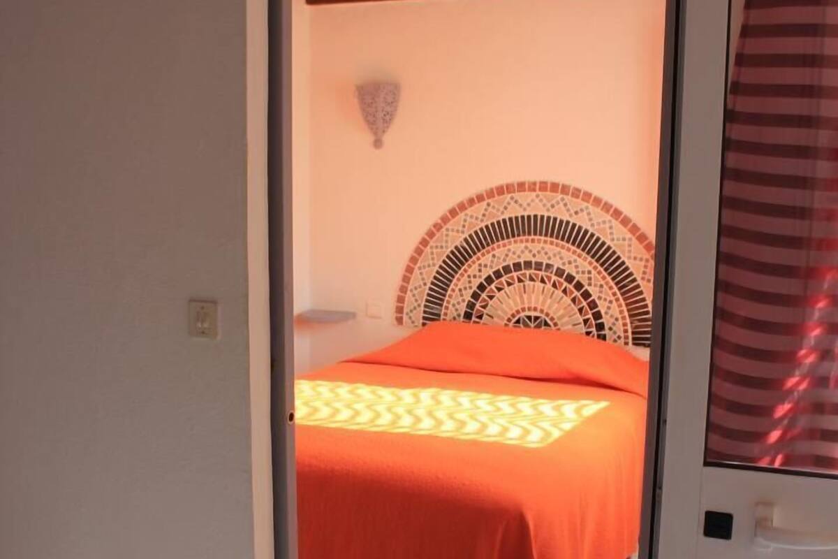 Ein Schlafzimmer mit einem Bett, einem gemusterten Kopfteil und einem Fliesenboden.