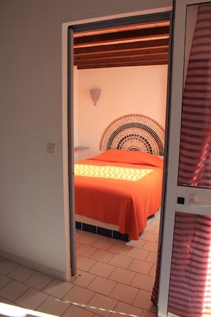 A room with a bed, a patterned headboard, and a tiled floor.