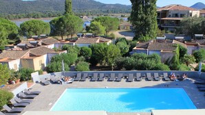 Piscina no terraço com espreguiçadeiras e vista dos edifícios e paisagem ao redor.