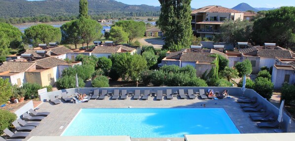A rooftop swimming pool with lounge chairs and a view of the surrounding buildings and landscape.